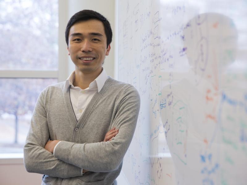 CSE Associate Professor Polo Chau stands in front of a white board with equations written on it.